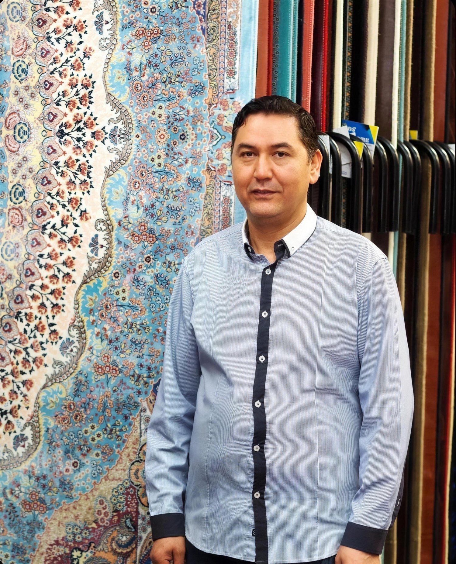Mohammad, owner of Dandy Rugs, in his Dandenong showroom in front of the rugs