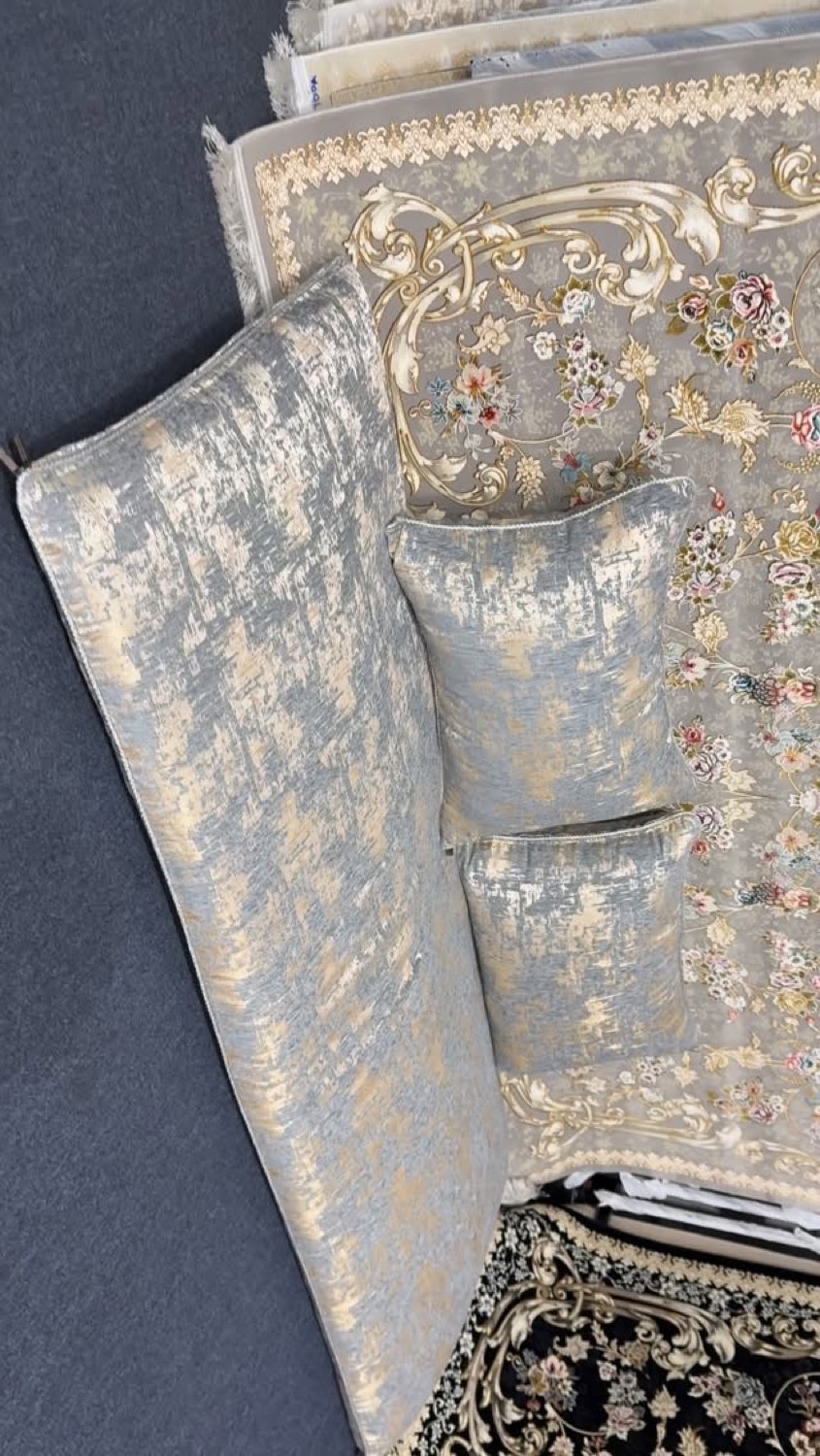 Velvet toshak cushions resting on ornate rugs in the showroom
